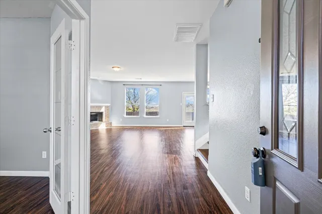 a view of a hallway with wooden floor and a living room
