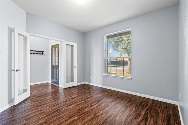 a view of an empty room with wooden floor and a window