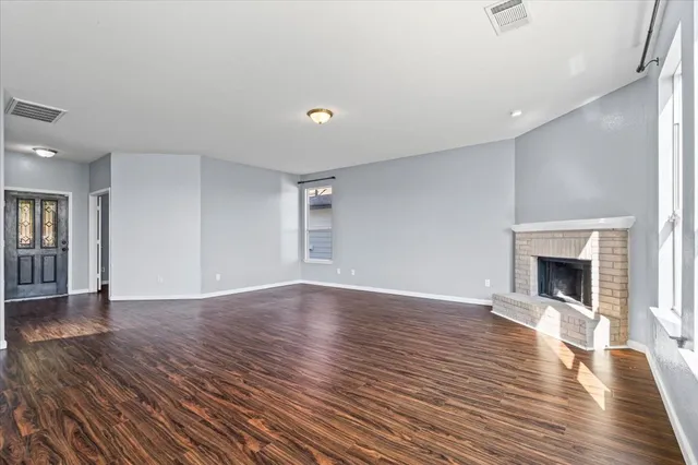 a view of empty room with wooden floor and fireplace