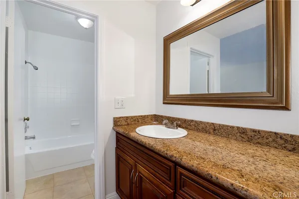 a bathroom with a granite countertop sink and mirror with bathtub