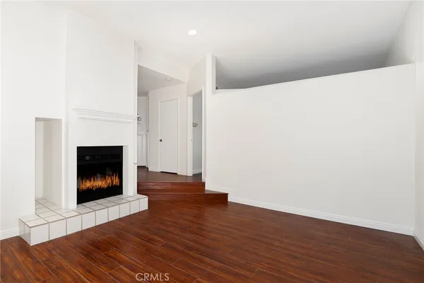 a view of an empty room with wooden floor and a fireplace