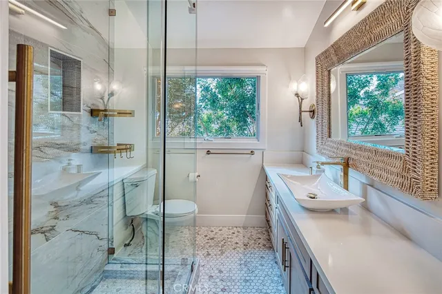 a bathroom with a granite countertop sink a toilet and shower