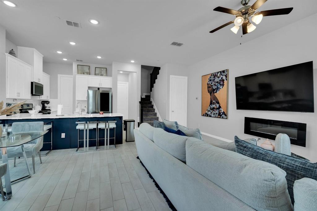 1498 Weston Road Dallas, TX 75234 - Photo 4 of 24 Open-concept living space featuring wood-finish flooring, a contemporary electric fireplace, and recessed lighting
