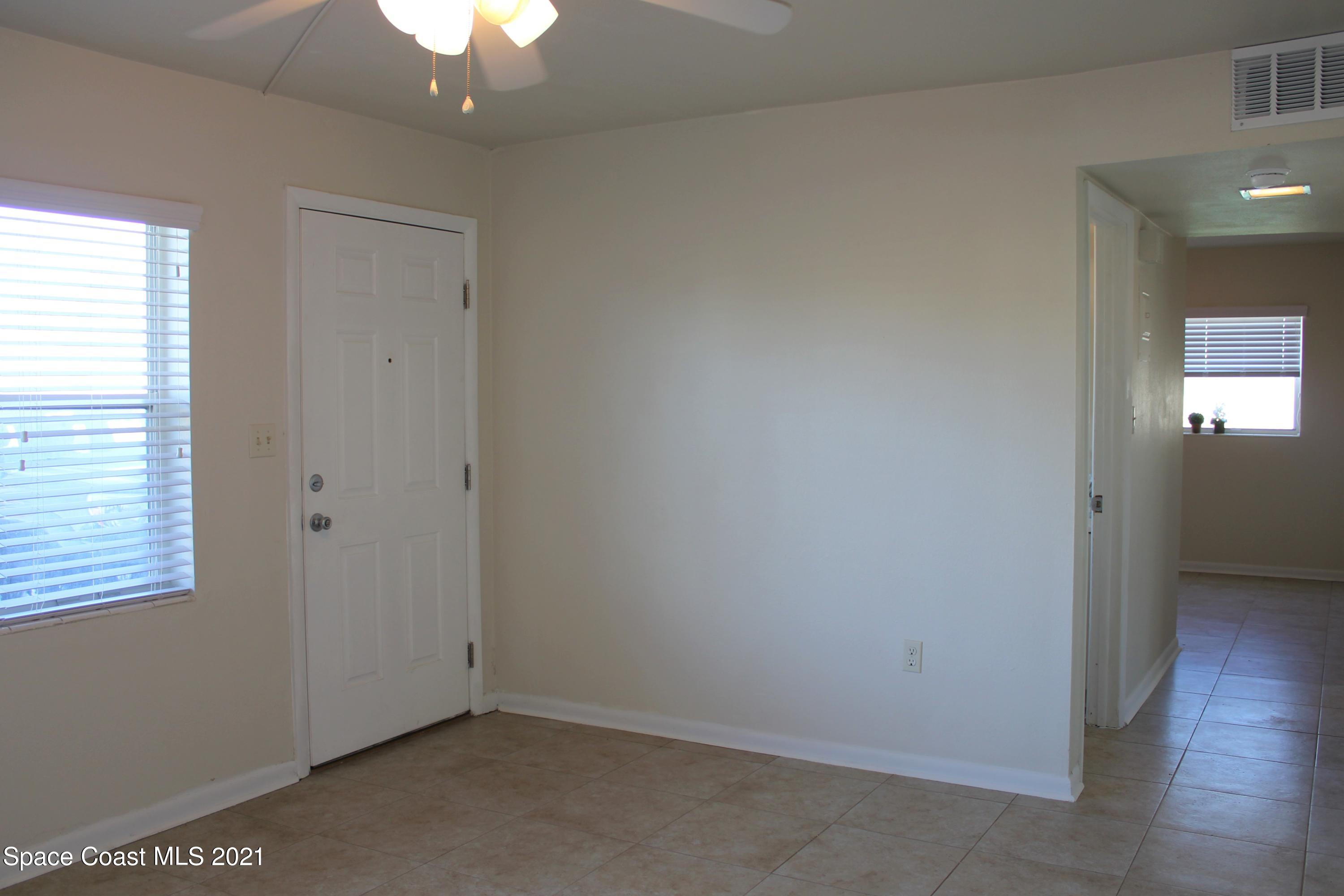 651 Palm Drive, Unit E1 Satellite Beach, FL 32937 - Photo 7 of 18 an empty room with wooden floor and windows