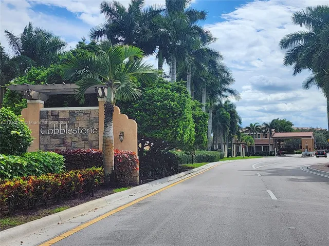a view of a street with potted plants and big trees