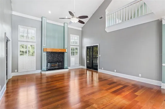 a view of an empty room with wooden floor fireplace and a window