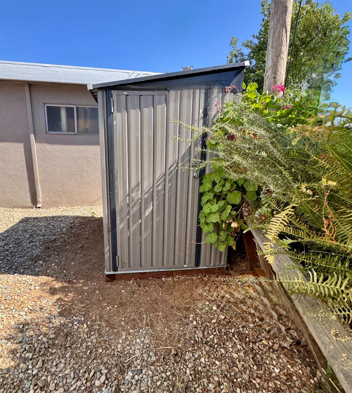 360 East Grant Line Road, Unit 16 Tracy, CA 95376 - Photo 23 of 36 Metal storage shed with a sloped roof, situated on a gravel and dirt surface