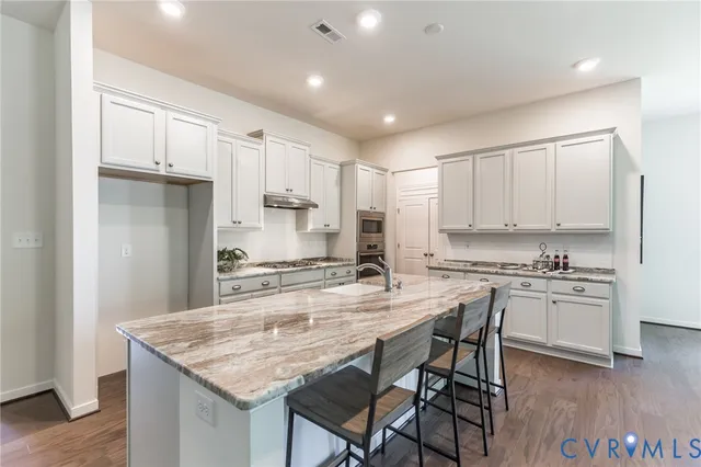 a kitchen with kitchen island granite countertop a table chairs stove and cabinets