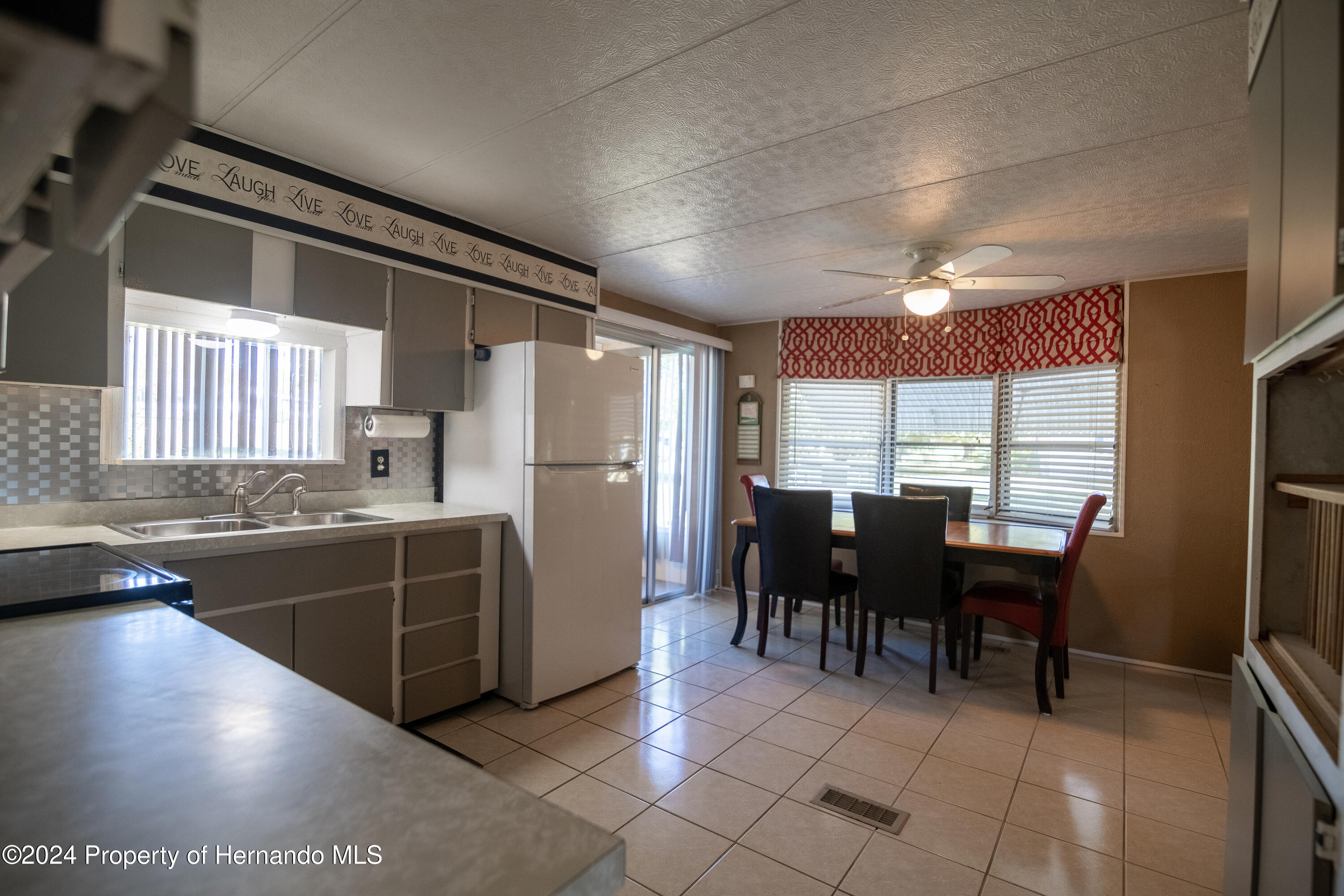 7526 Highpoint Boulevard Brooksville, FL 34613 - Photo 25 of 30 a kitchen with refrigerator cabinets dining table and chairs