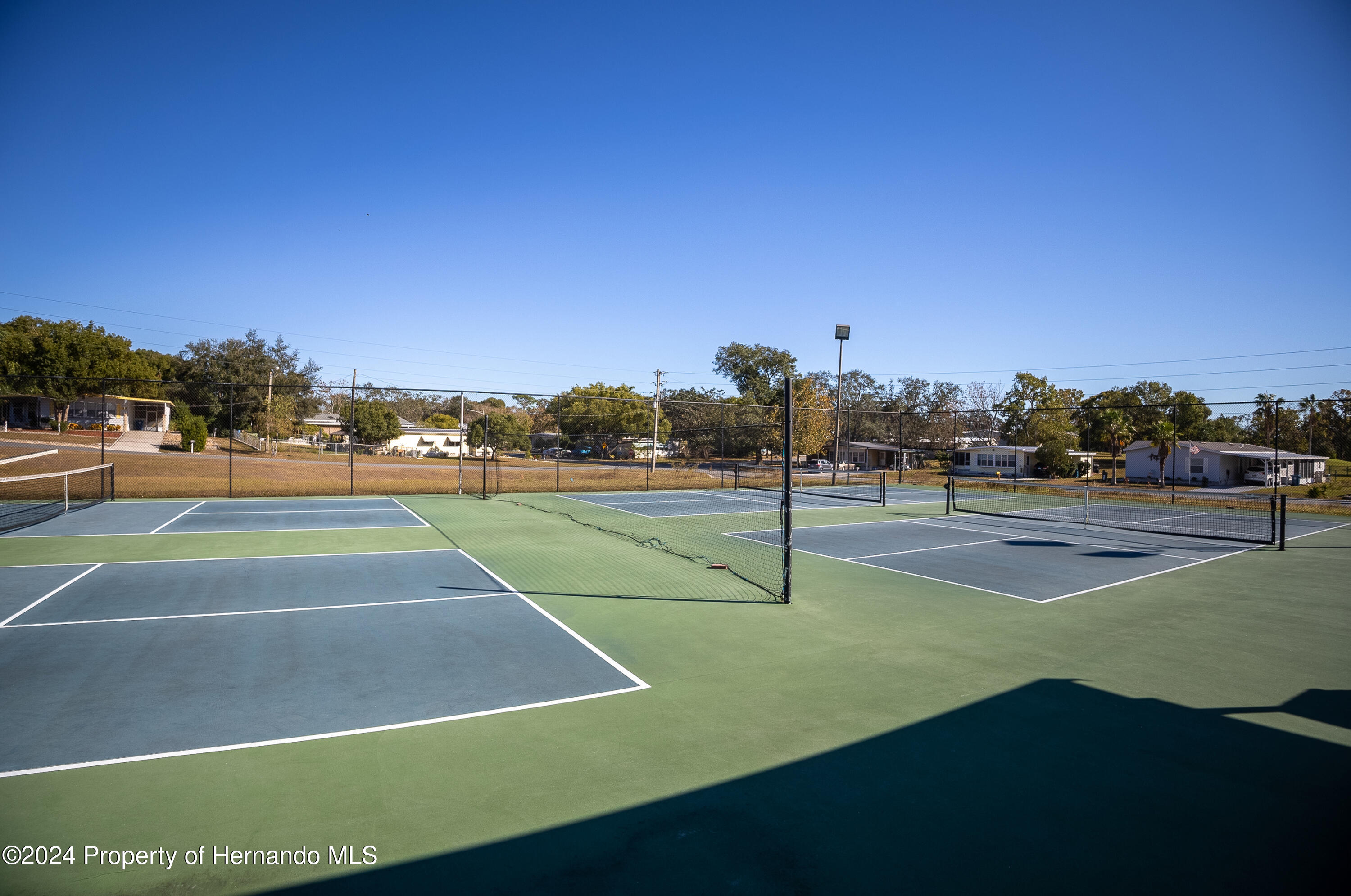 7526 Highpoint Boulevard Brooksville, FL 34613 - Photo 29 of 30 a tennis court with trees in the background