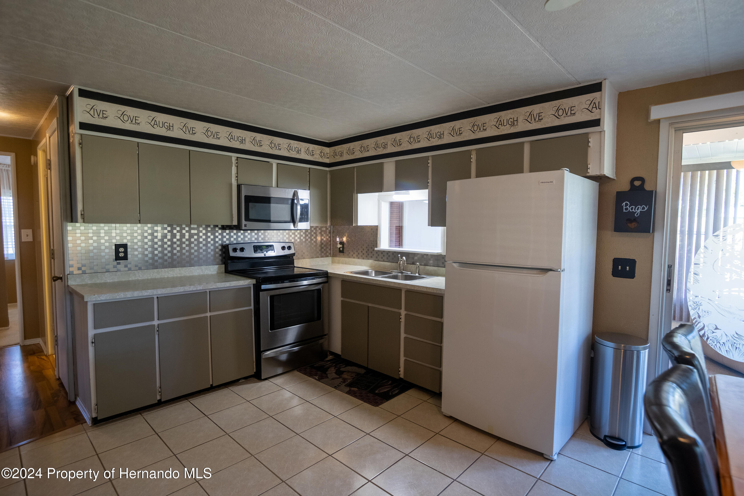 7526 Highpoint Boulevard Brooksville, FL 34613 - Photo 10 of 30 a kitchen with white cabinets and white appliances