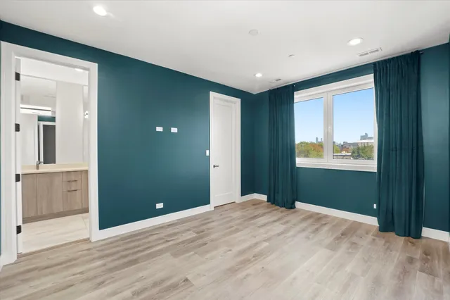 a bedroom with wooden floor and bathroom