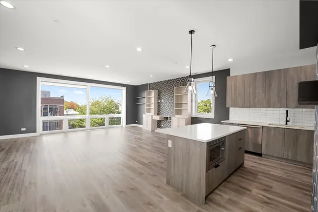 a kitchen with stainless steel appliances granite countertop a sink a stove and a large window