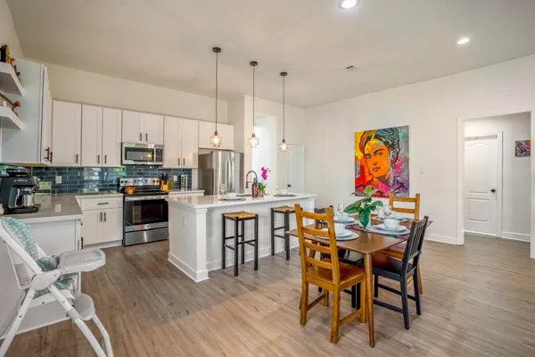 a kitchen with stainless steel appliances granite countertop a dining table chairs and granite counter tops