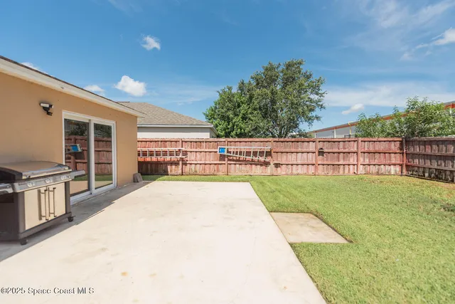 a view of swimming pool with seating space and trees in the background