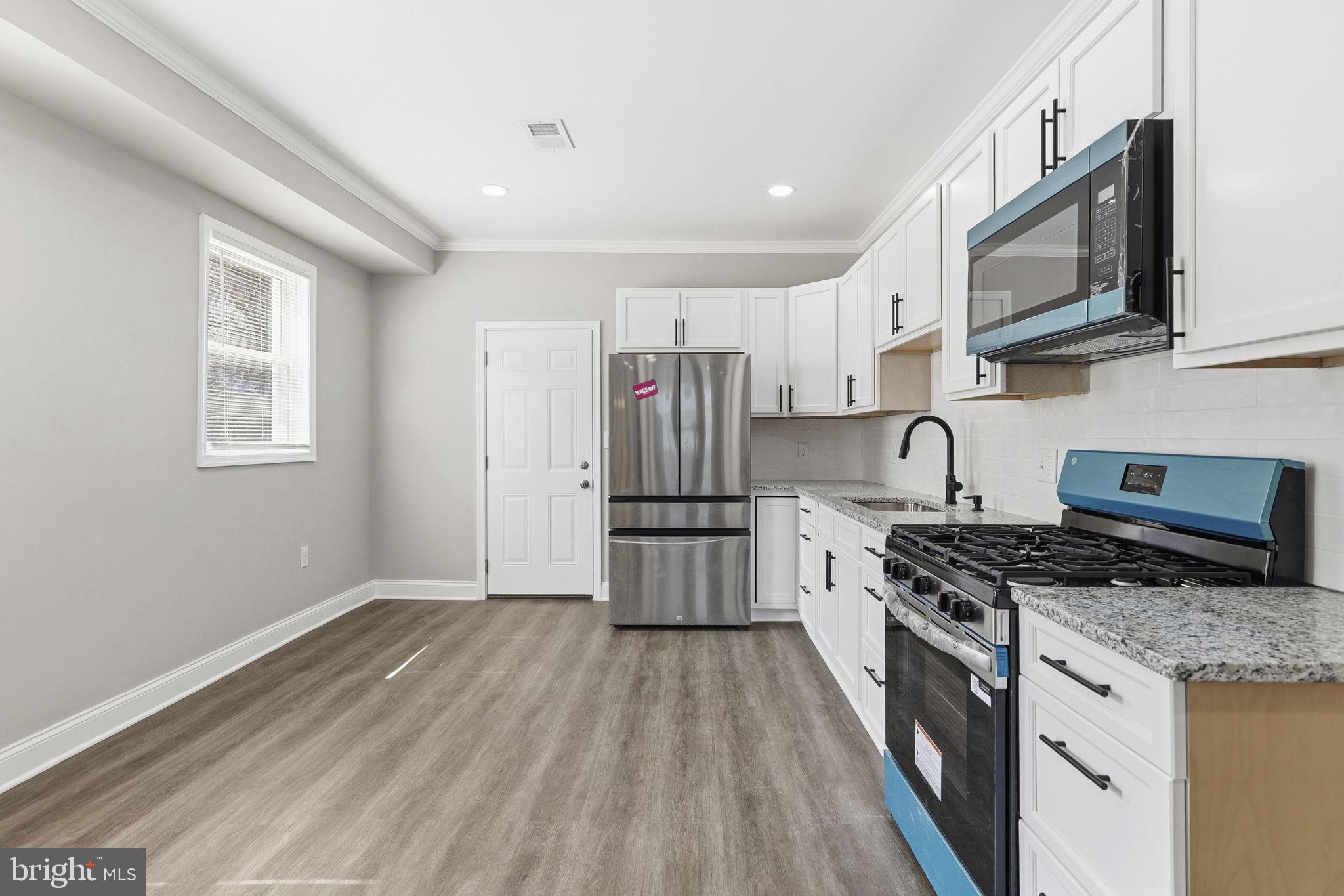 1200 North Dukeland Street Baltimore, MD 21216 - Photo 4 of 17 a kitchen with stainless steel appliances granite countertop a stove a sink and a refrigerator