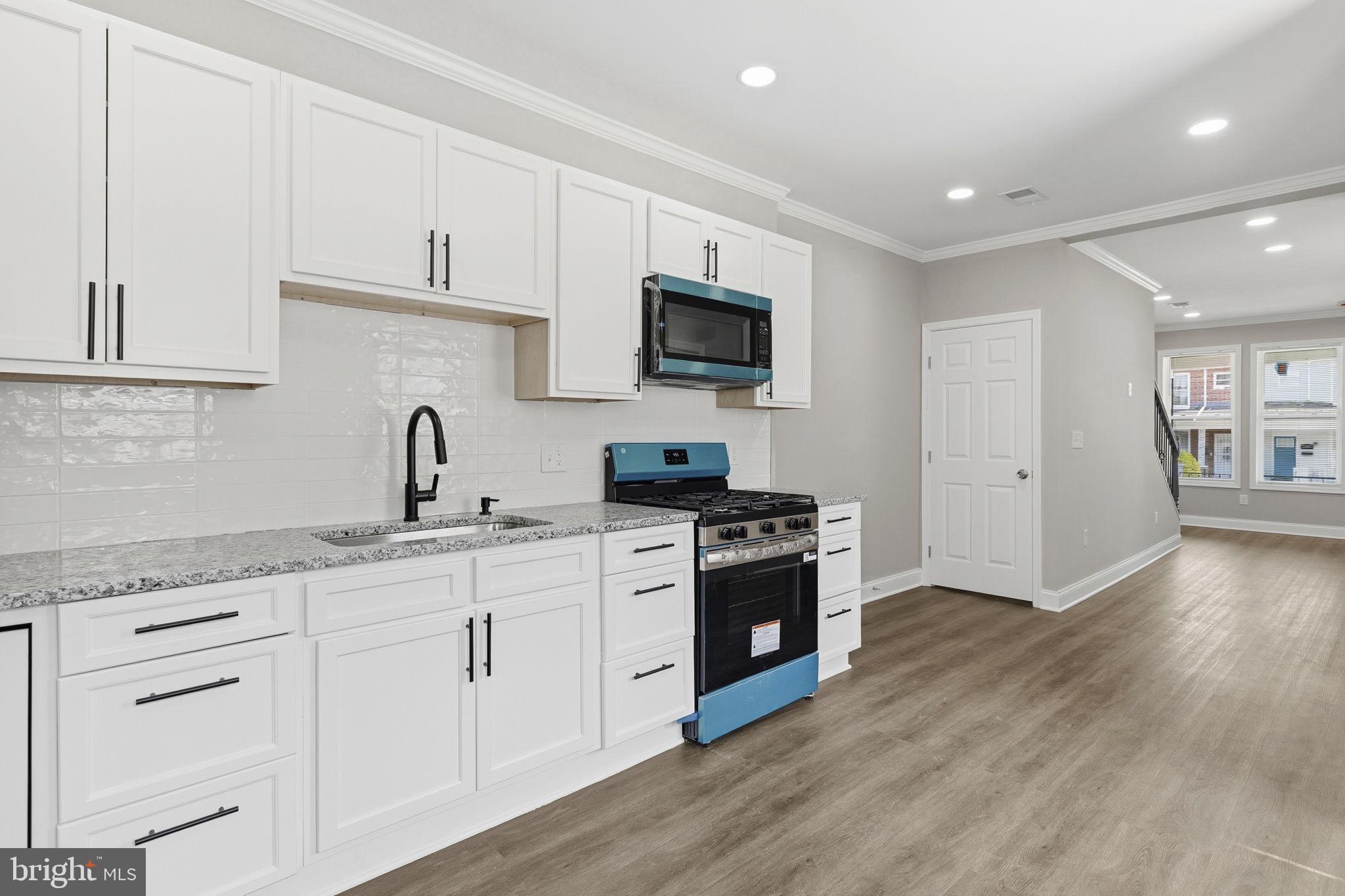 1200 North Dukeland Street Baltimore, MD 21216 - Photo 5 of 17 a kitchen with granite countertop a sink and a stove top oven