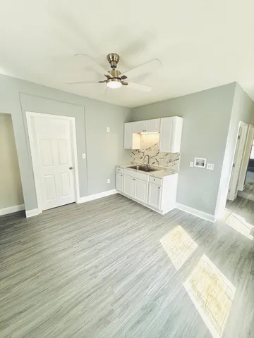 a view of an empty room with wooden floor and cabinet