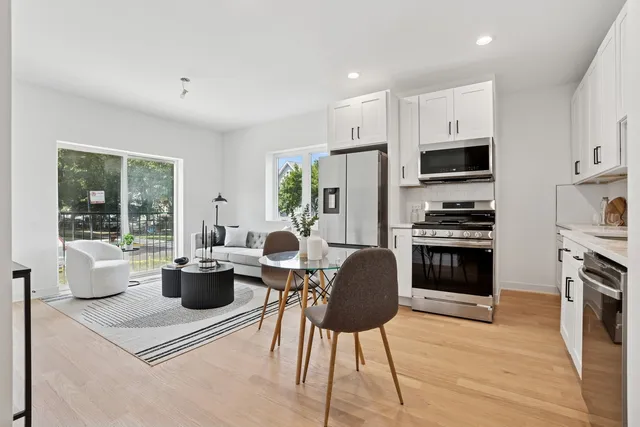 a open kitchen with stainless steel appliances granite countertop a stove top oven a sink dishwasher a dining table and chairs with wooden floor