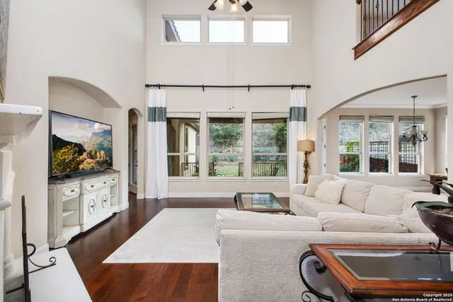 a living room with furniture a flat screen tv and floor to ceiling window