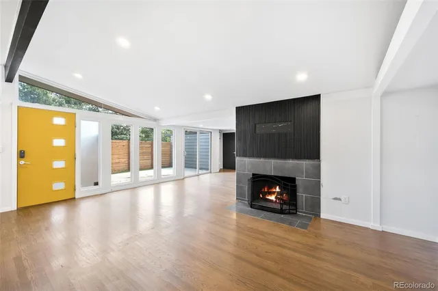 a view of an empty room with wooden floor fireplace and a window