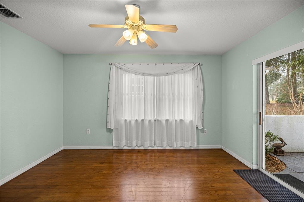 10891 Southwest 69th Circle Ocala, FL 34476 - Photo 18 of 28 an empty room with wooden floor chandelier fan and windows