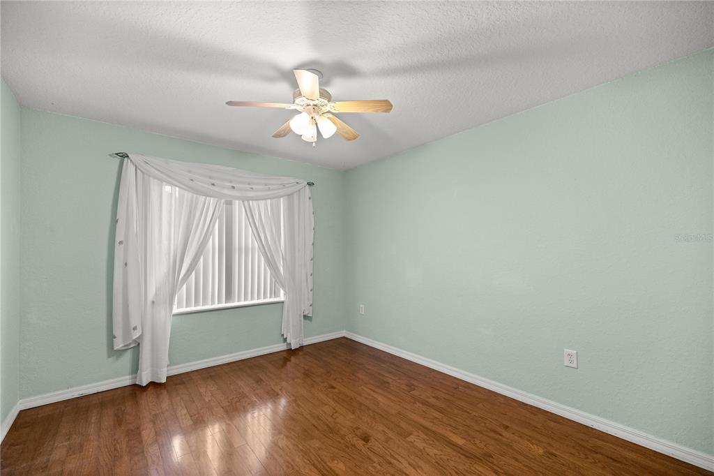 10891 Southwest 69th Circle Ocala, FL 34476 - Photo 20 of 28 an empty room with wooden floor chandelier fan and windows