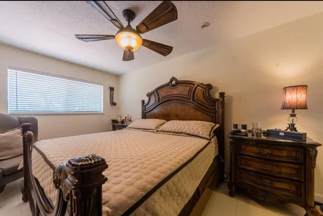 a view of a patio with table and chairs under an umbrella with large trees