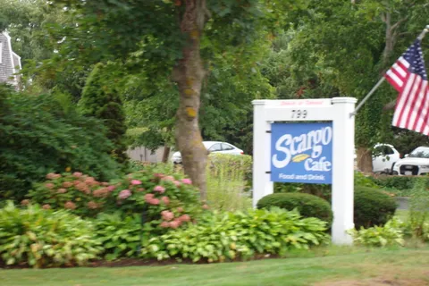 a sign that is sitting in the grass next to a road