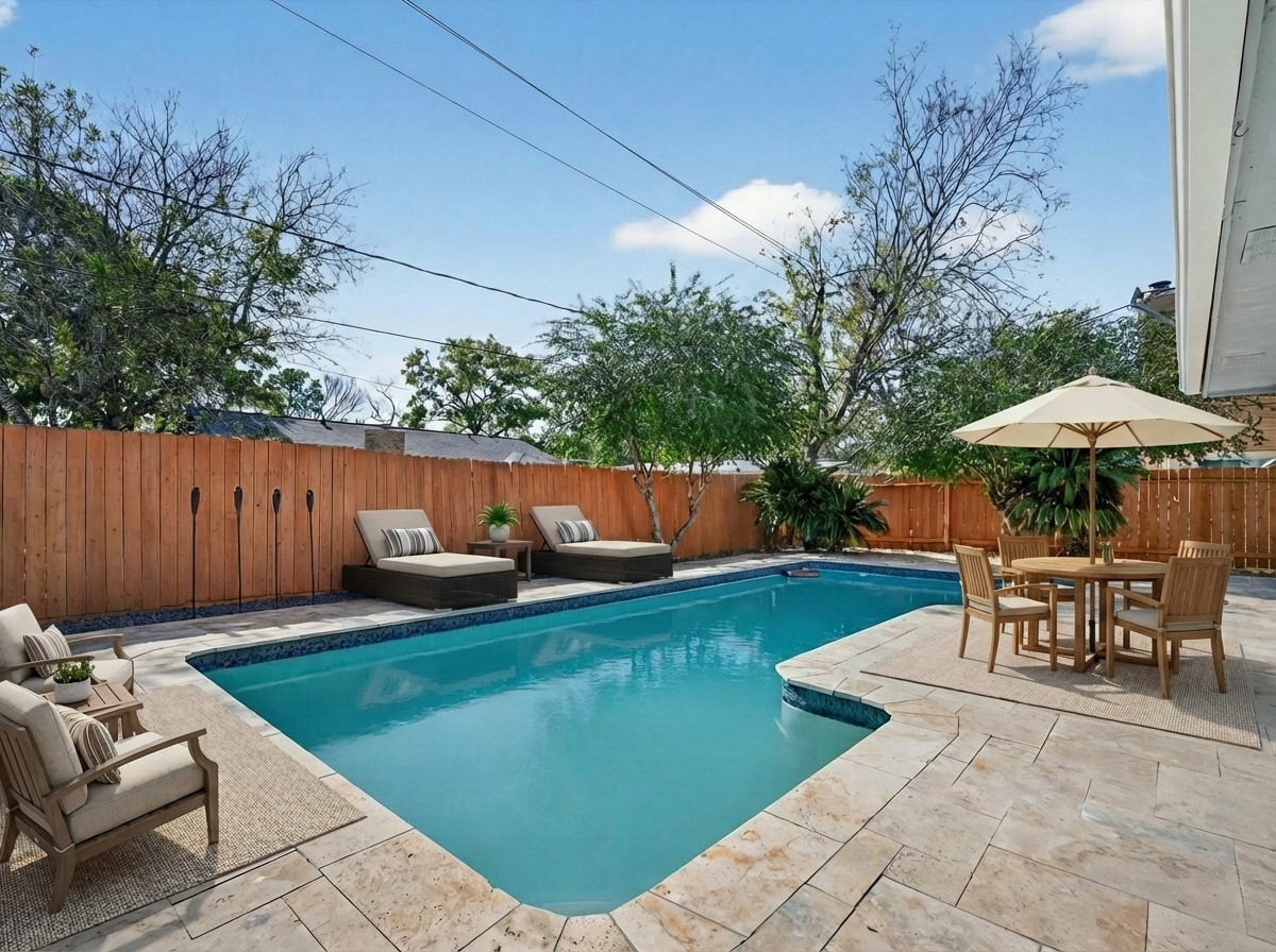 a view of a backyard with furniture and a table and chairs under an umbrella