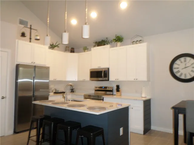 a kitchen with stainless steel appliances kitchen island a table chairs in it and wooden floors