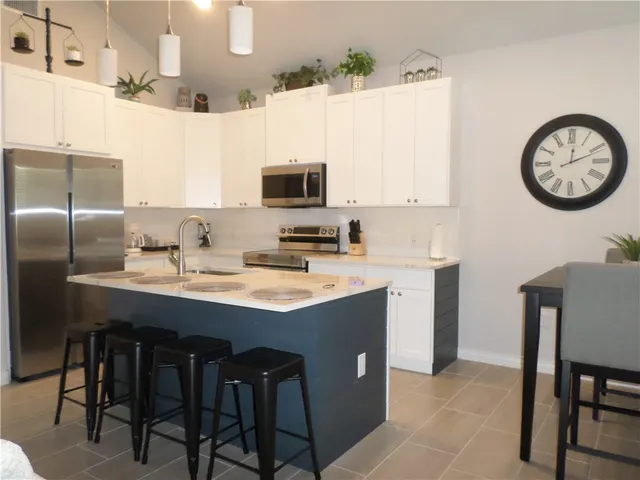 a kitchen with stainless steel appliances granite countertop a sink a stove a refrigerator with a dining table and chairs