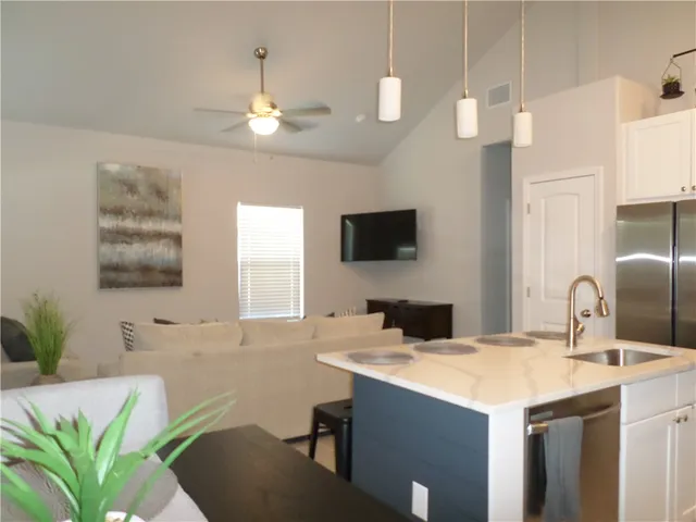 a kitchen with a sink a counter top space and living room view