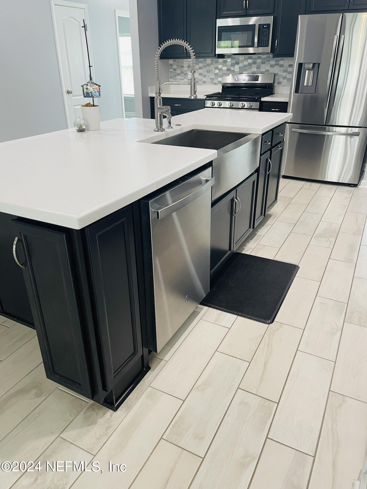 86508 Secluded Place Yulee, FL 32097 - Photo 6 of 43 a kitchen with stainless steel appliances a sink a stove a refrigerator a microwave and cabinets