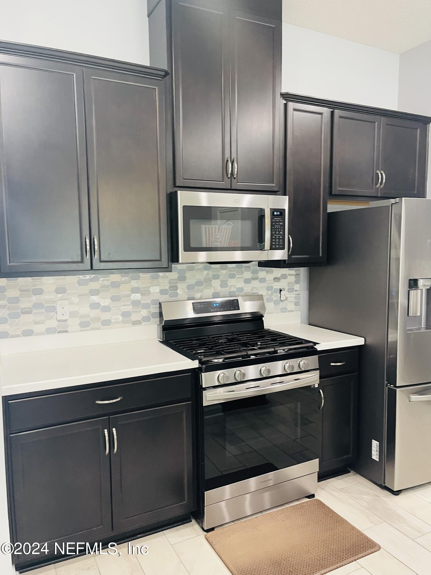 86508 Secluded Place Yulee, FL 32097 - Photo 10 of 43 a kitchen with granite countertop a refrigerator and a stove top oven