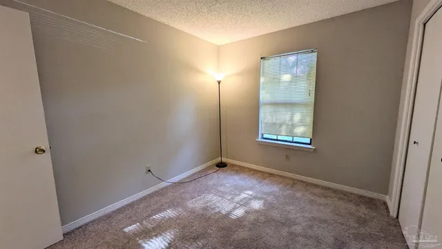 a view of an empty room with window and closet area