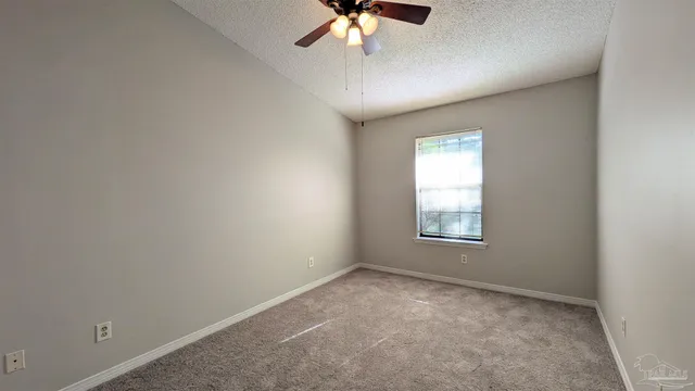 an empty room with a chandelier fan and windows