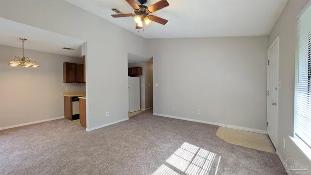 an empty room with chandelier fan and windows