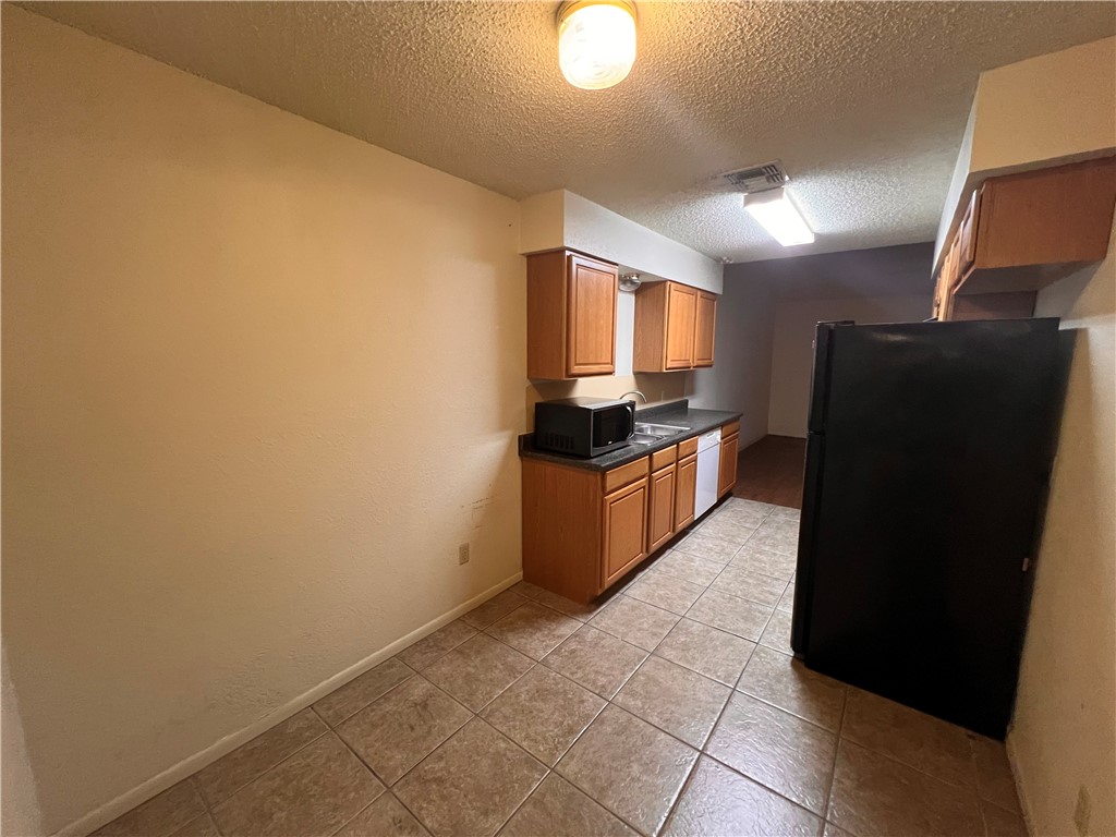 4021 Acushnet Drive, Unit F Corpus Christi, TX 78413 - Photo 3 of 21 a kitchen with a refrigerator and a stove top oven