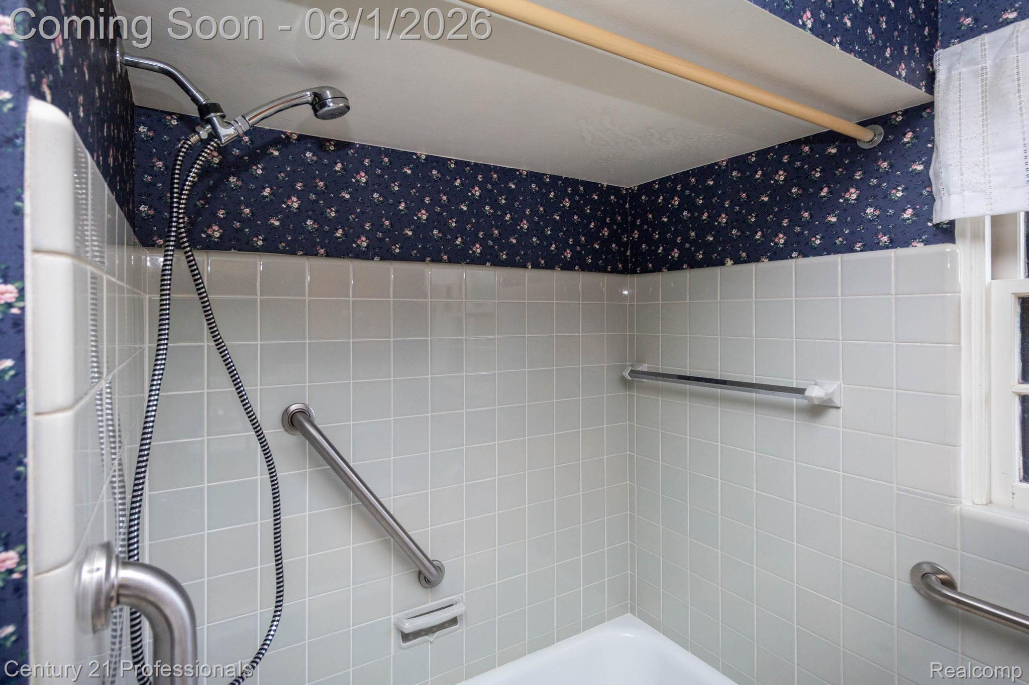 1365 East Buell Road Rochester, MI 48306 - Photo 18 of 56 Bathtub with white tile surround, a handheld shower fixture, and multiple grab bars