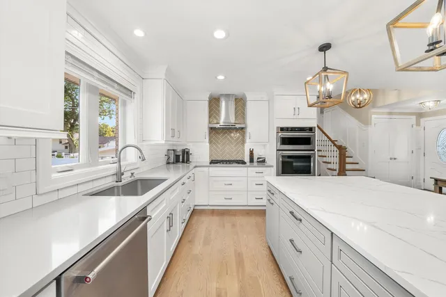 a large kitchen with stainless steel appliances kitchen island granite countertop a sink dishwasher a stove and a dining table with wooden floor