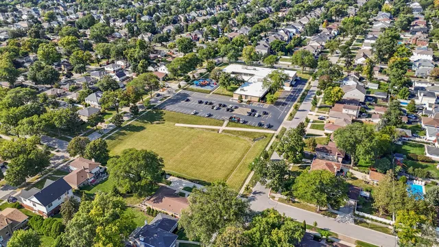 an aerial view of a residential houses with outdoor space and trees all around