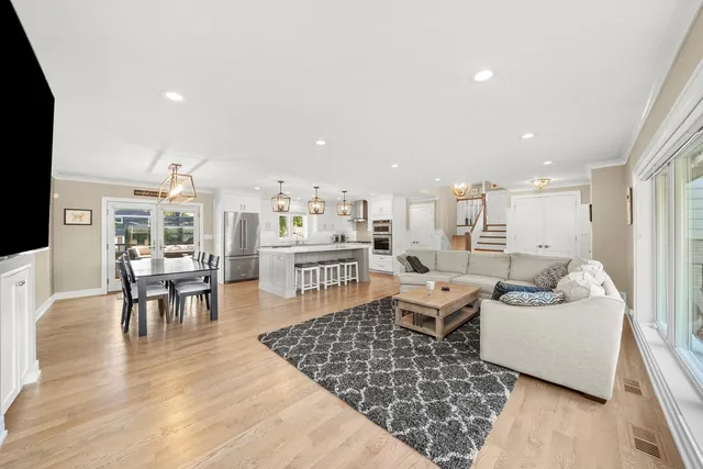 a living room with furniture and a dining table with wooden floor
