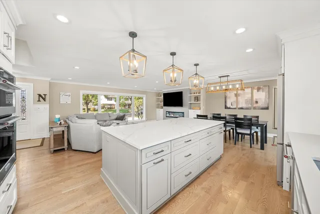 a large kitchen with kitchen island white cabinets and stainless steel appliances