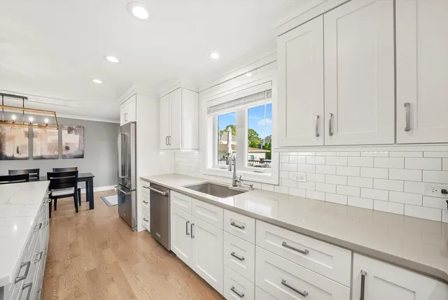 a kitchen with white cabinets and sink