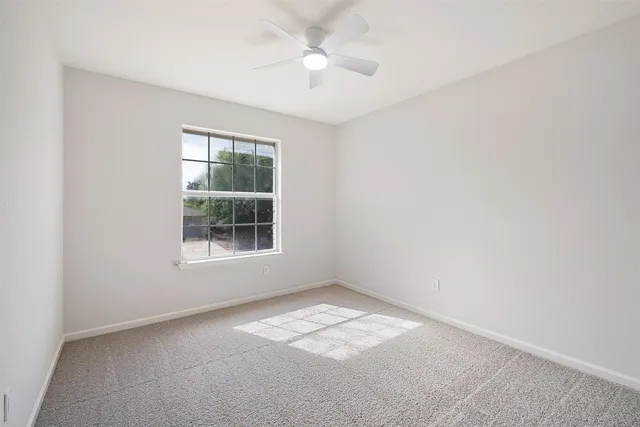 an empty room with a window and a fan