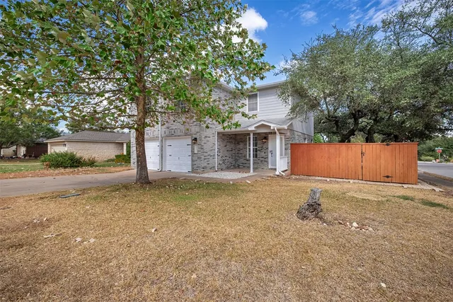 a backyard of a house with wooden fence and large tree