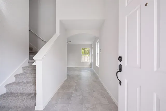 a view of a hallway with white walls and stairs