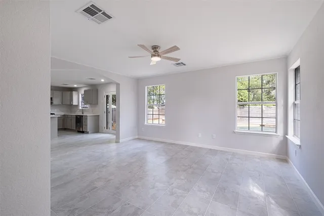 an empty room with windows and chandelier fan