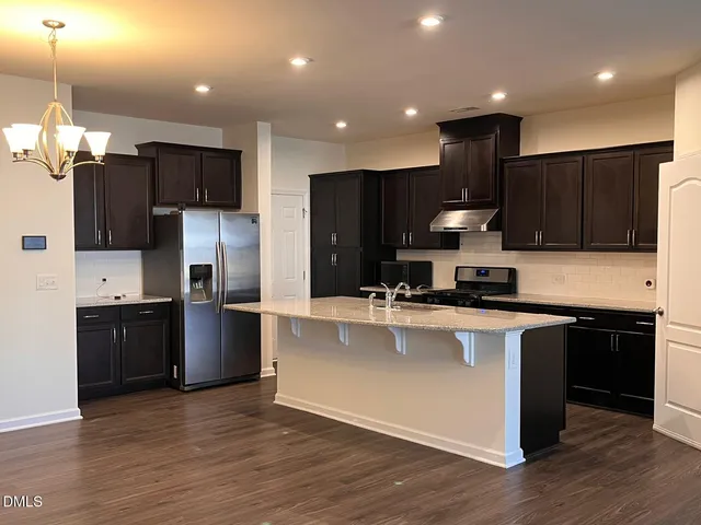 a large kitchen with stainless steel appliances kitchen island granite countertop a refrigerator a sink dishwasher a stove and a microwave oven on granite countertops